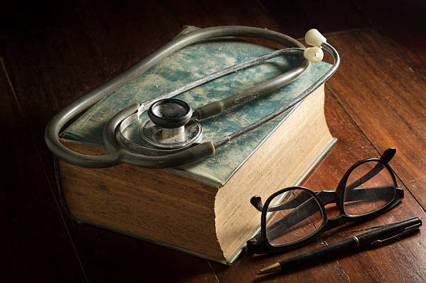 стетоскоп и очки, ручка и антикварная книга. - book book cover healthcare and medicine medical exam стоковые фото и изображения