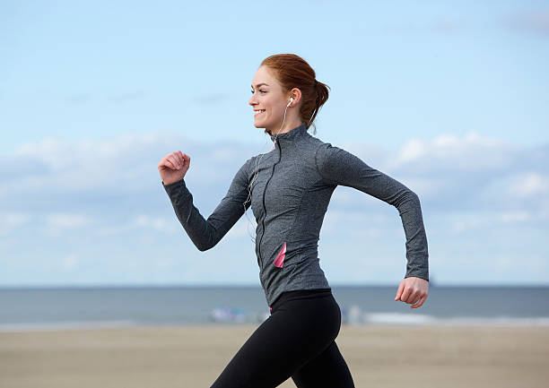 Smiling woman jogging at the sea side Profile portrait of a smiling woman jogging at the sea side racewalking photos stock pictures, royalty-free photos & images