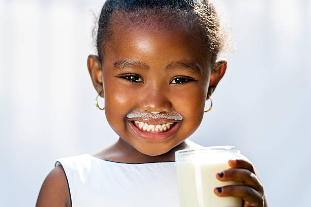 jolie fille africaine montrant blanc lait moustache. - milk child drinking little girls photos et images de collection