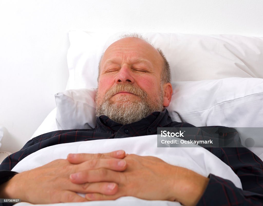 Elderly care portrait of an elderly man holding his hands in the bed Sleeping Stock Photo