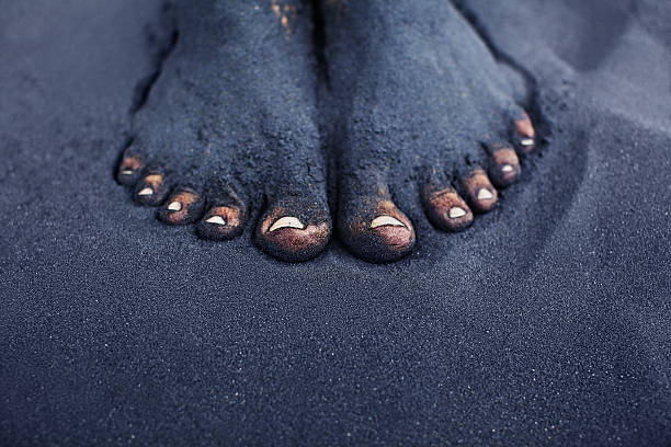 Dirty woman bare feet in black sand Photo of dirty woman bare feet in black sand. People relaxation, fun and walking barefoot by black volcanic sand on ocean beach. Travel lifestyle, family summer vacation on tropical island. volcanic landscape photos stock pictures, royalty-free photos & images