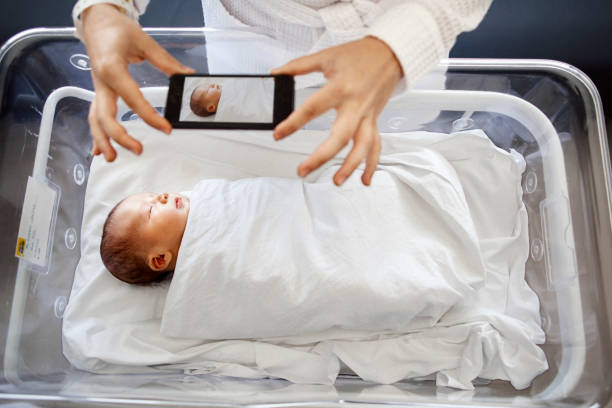 Mother photographing newborn son
