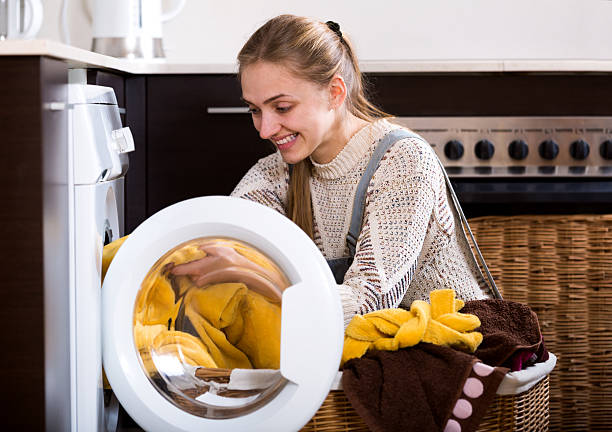 istock Young woman taking clothes out washing machine 537359090