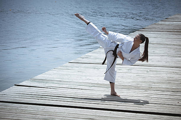 Young woman practising karate outdoors. Full length, side view, copy space has been left. Part of the series.