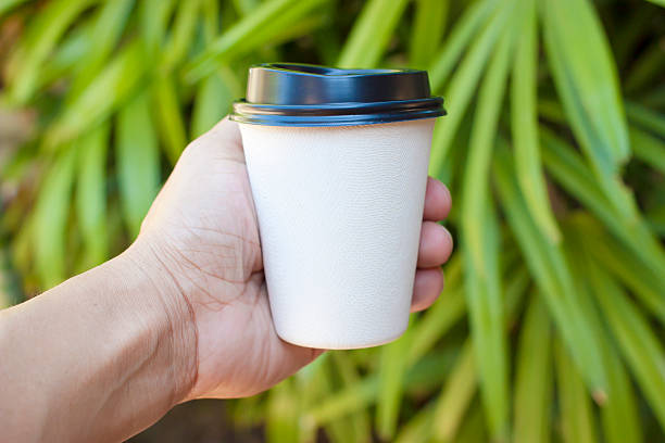 istock Hand holding paper coffee cup with green nature 537362554