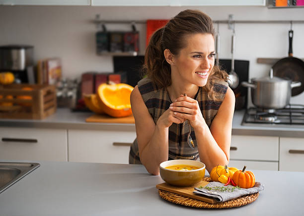 istock young housewife eating pumpkin soup in kitchen 537366571