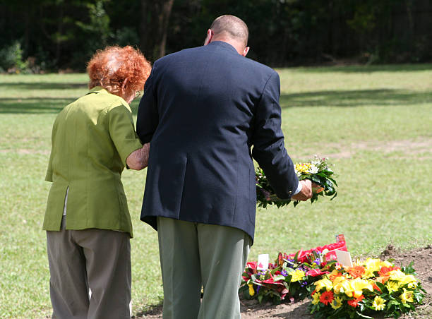 ANZAC Day Veteran and Widow Lay a Floral Wreath Gold Coast, Australia - 25 April, 2010: An elderly widow, accompanied by a well-dressed Army veteran, lays a floral wreath on an ANZAC Day war memorial on the Gold Coast. larrikin stock pictures, royalty-free photos & images