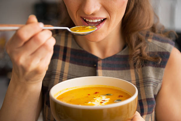 closeup on young woman eating pumpkin soup in kitchen