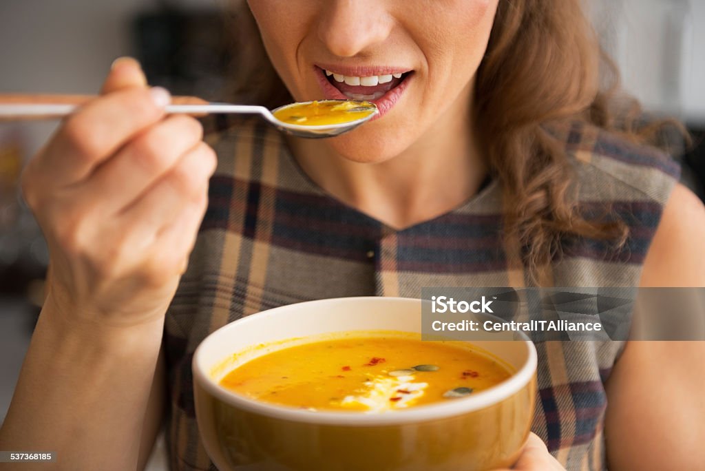 closeup on young woman eating pumpkin soup in kitchen Closeup on young woman eating pumpkin soup in kitchen Soup Stock Photo