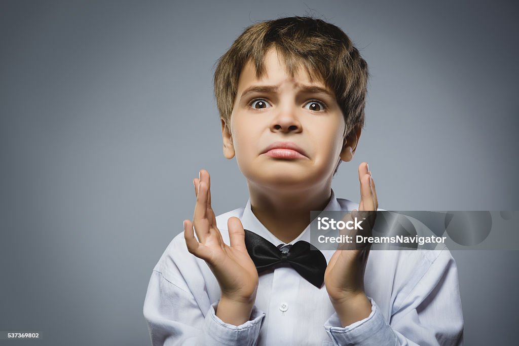 Closeup Portrait of handsome boy with astonished expression while standing Closeup Portrait of handsome boy with astonished expression while standing against grey background. Adult Stock Photo