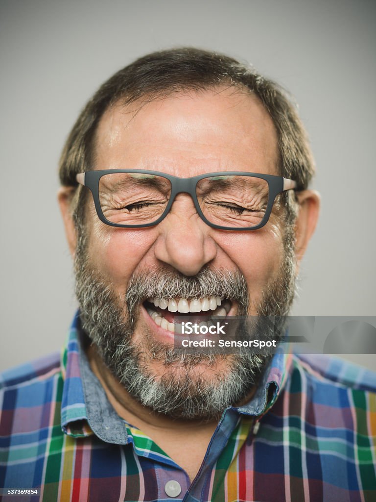 Portrait of a real spanish man with glasses and beard. Vertical portrait of a real spanish man with excited expression. Studio DSLR photography with sharp focus on eyes. The man wears modern glasses and shirt and has a grey beard. Sharp focus on eyes. Portrait Stock Photo