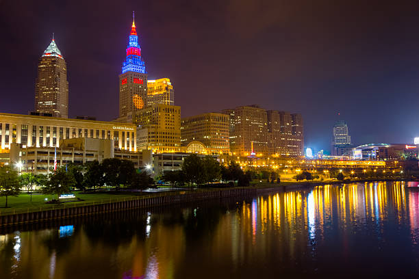 Cleveland Aglow at Night Reflecting on the Cuyahoga River Cleveland cityscape with a view of Key Tower, Terminal Tower, 200 Public Square (also known as the BP Building) and the Cuyahoga River just after sunset. terminal tower stock pictures, royalty-free photos & images