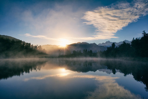 Dawn on New Zealand's South Island, and the Southern Alps are reflected in the mirror-like surface of Lake Matheson.