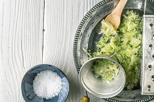 istock Grated cucumber with strainer and salt on white table 537374506