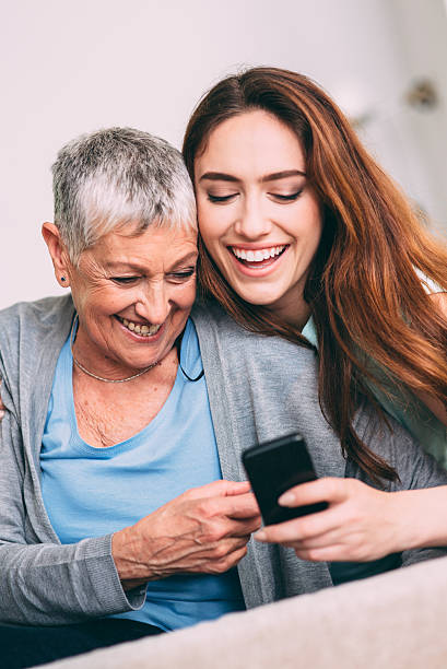 mãe e filha texring - wireless technology cheerful granddaughter grandmother imagens e fotografias de stock