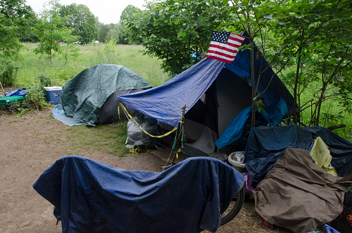 Portland, Oregon, USA-May 26, 2016: Homeless campsite in a field near the Springwater Corridor pedestrian walkway in Southeast Portland, Oregon. The homeless population has become more visible as housing in Portland becomes less affordable.