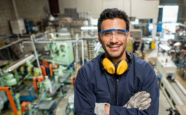 Man working at a factory Latin American man working at a metal factory and wearing protective wear manufacturing occupation stock pictures, royalty-free photos & images