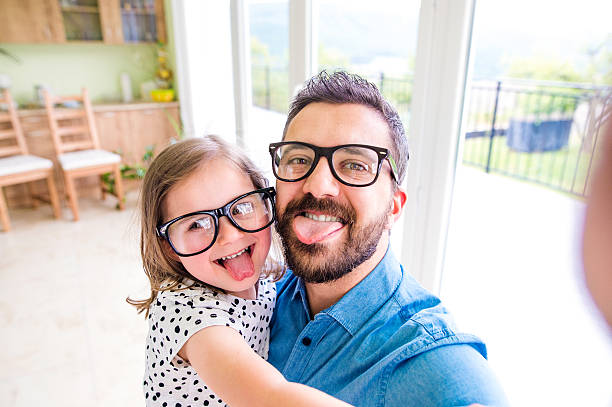 pai com sua pequena menina emperramento língua de fora - glasses child cute offspring imagens e fotografias de stock