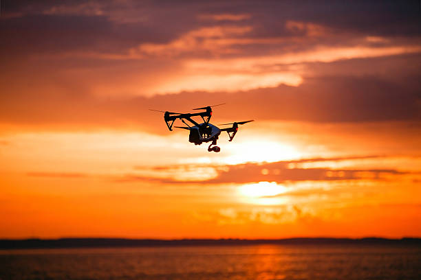 istock quadrocopter drone with remote control. Dark silhouette against colorfull sunset 537381244