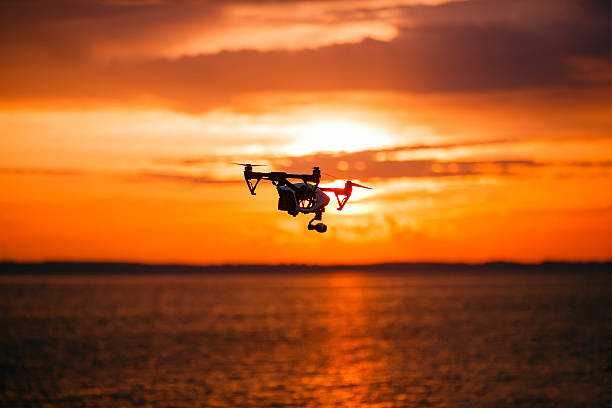 istock quadrocopter drone with remote control. Dark silhouette against colorfull sunset 537381296