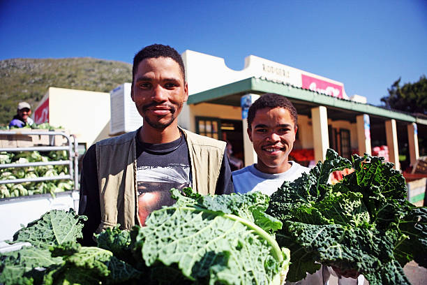Cape Town, South Africa - September 17, 2007:  Smiling workers pose with the fresh produce they are offloading from the truck at the left for sale in a traditional South African greengrocer's store.