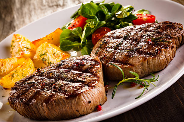 istock Beef steaks, baked potatoes and vegetable salad 537383816