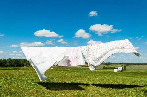  Laundry drying in a wind, white sheets on a wind in nature background, housework concept