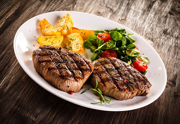 istock Beef steaks, baked potatoes and vegetable salad 537384080