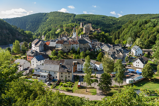 Esch-sur-Sure is a small town near Luxembourg city that sits in a little circle of land within a sharp curve of the river Sure. It is very picturesque and has the ruins of an old castle on top of the hill. The town is surrounded by lush, green trees.