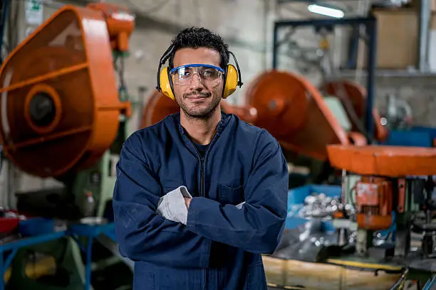 Latin American man working at a factory and looking at the camera smiling