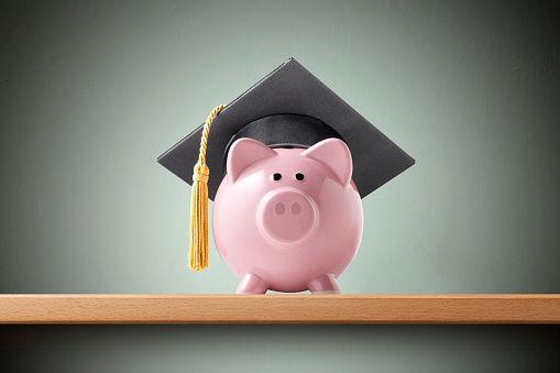 Piggy bank with graduation cap on the shelf.