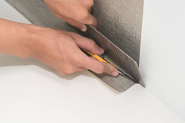 istock Handyman putting up wallpaper on the white walls 537390518