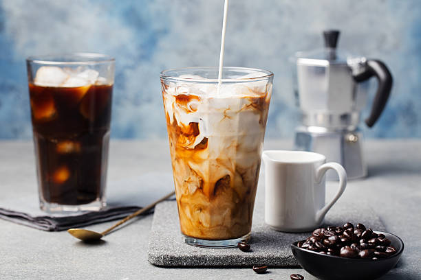 Ice coffee in a tall glass with cream poured over Ice coffee in a tall glass with cream poured over and coffee beans on a grey stone background vietnamese culture photos stock pictures, royalty-free photos & images