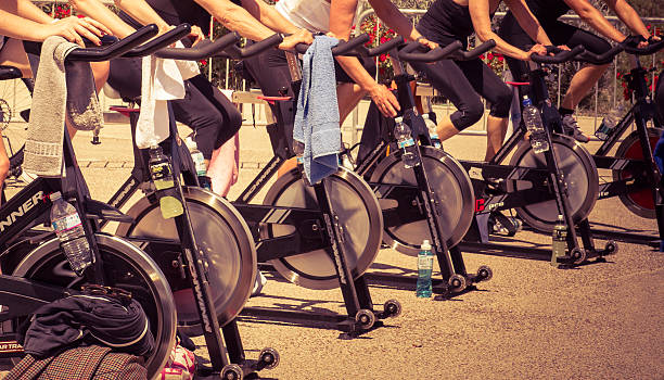 Urban exercising Imperia, IM, Italy - May 18, 2014: People perform a exercising session outdoors in an urban park of liguria. Athlets training an their special bikers to keep healthy spin bike stock pictures, royalty-free photos & images