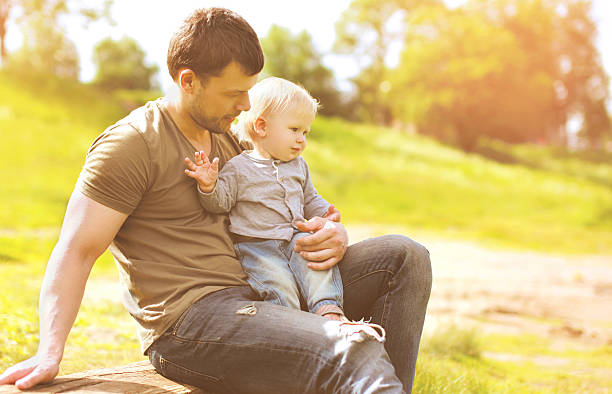 istock Happy father and son resting sitting together on grass summer 537396112