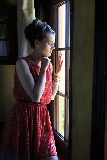 Photo of Lonely woman looking through the window