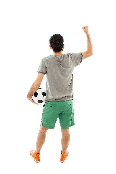 Young man holding soccer ball in hand looking at wall