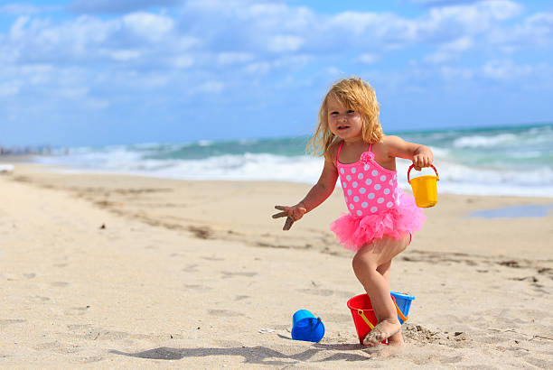 istock cute little girl play with sand on beach 537398686