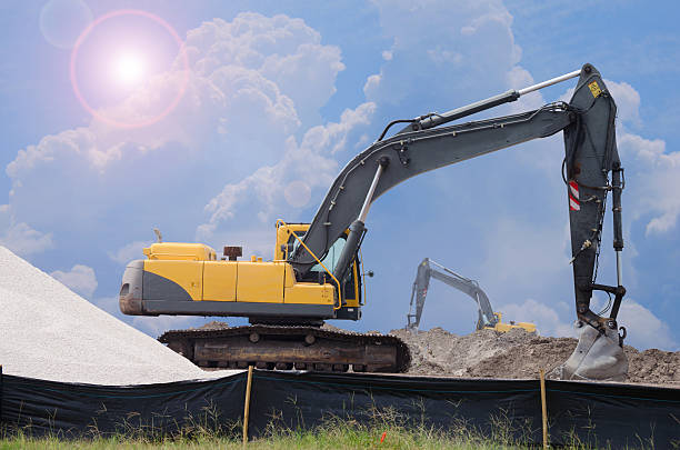Sunny bulldozers construction site work digging Bulldozers at work scooping and digging  dirt working at a construction site on a bright day with the sun bursting around the clouds. silt stock pictures, royalty-free photos & images