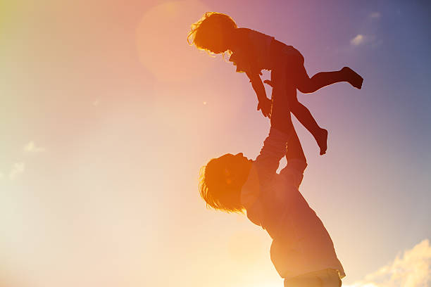 istock Father and little daughter silhouettes play at sunset 537399526