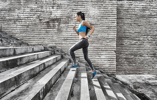 istock Sportswoman running up on stone stairs-side view 537402638