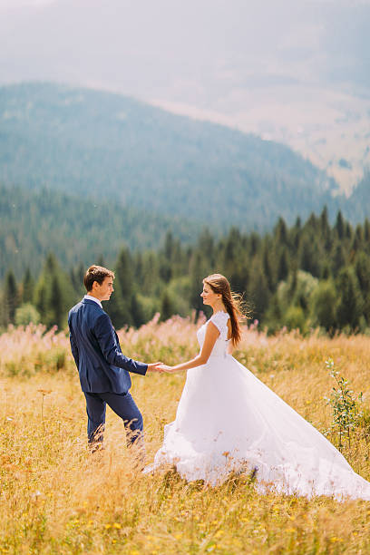 istock Beautiful young wedding couple walking on sunny field with forest 537402806