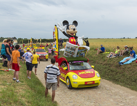 Quievy,France - July 07, 2015: Mickey Mouse caravan  during the passing of the Publicity Caravan on a cobblestoned road in the stage 4 of Le Tour de France on July 7 2015 in Quievy, France.
