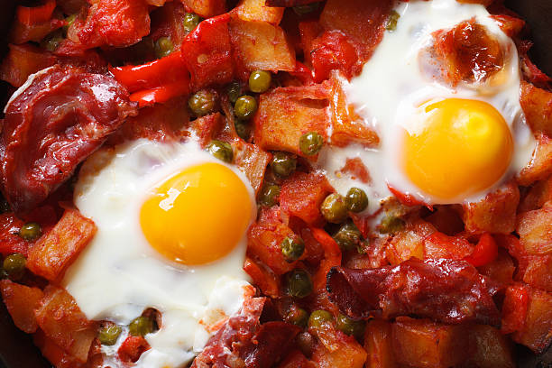 istock Fried eggs with chorizo, potatoes, peas and tomato close up 537403297