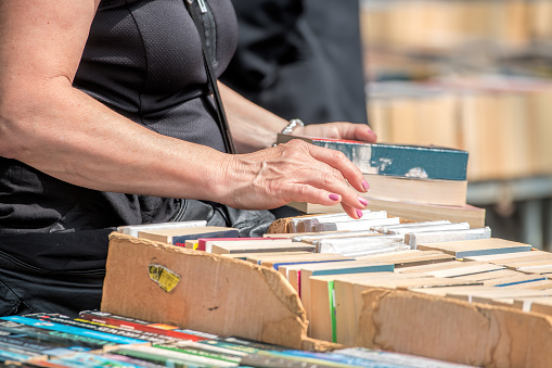 Woman Browsing Second Hand Books At Market Stall