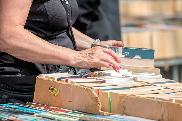 Woman Browsing Second Hand Books At Market Stall