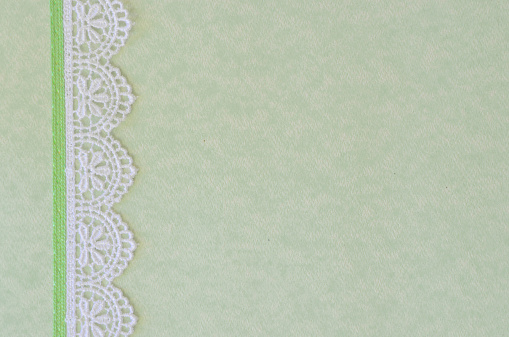 Pretty floral lace border on pastel green colored paper that can be used as a background for scrapbooking, cards, or invitations