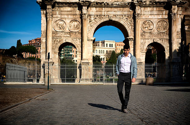 Stylish young man in front of Arco di Costantino, Rome, Stylish handsome young man walking in front of Arco di Costantino in Rome, Italy costantino stock pictures, royalty-free photos & images