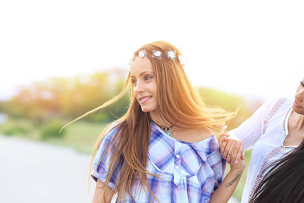 Two beautiful young women having fun on the villige road. Wears casual clothes and wreat. Nature and sunlight on background.