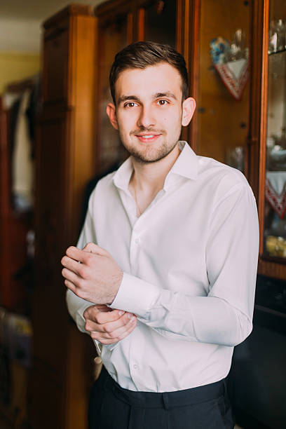 istock Young handsome man in white shirt dressing cufflinks indoors 537406946